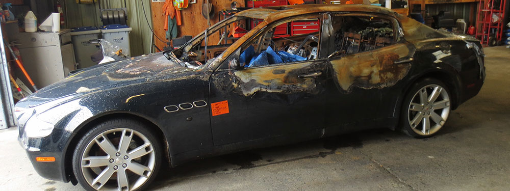 A fire-damaged passenger vehicle photographed in a workshop bay.